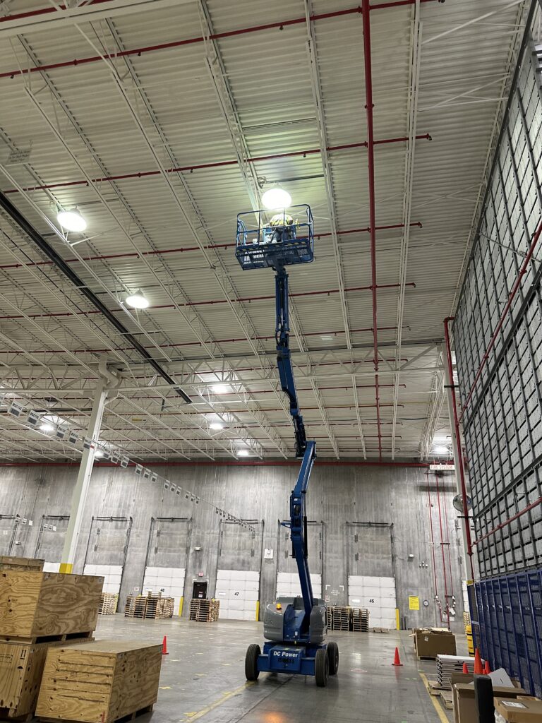 High-bay warehouse lighting installation using boom lift by Del Haven Electric in Western Washington