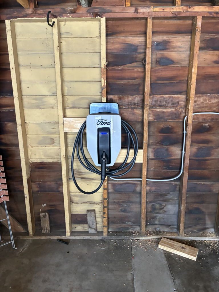 Ford Level 2 EV charger installed on open wood stud wall by Del Haven Electric