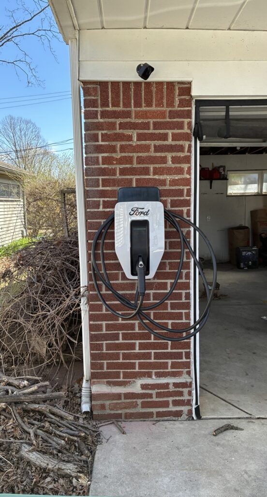 Ford Level 2 EV charger installed on brick exterior wall by Del Haven Electric