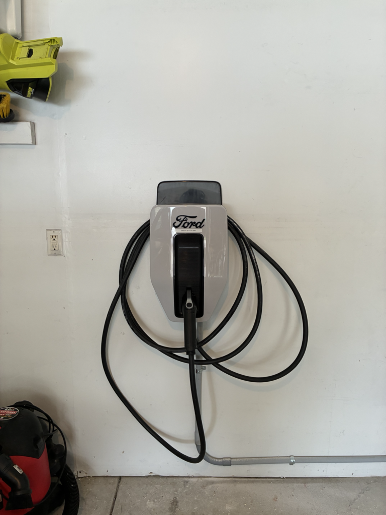 Ford Level 2 EV charger installed on interior garage wall by Del Haven Electric