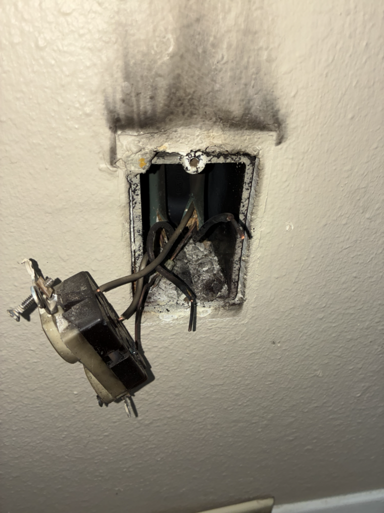 Burned electrical outlet with damaged wiring before replacement